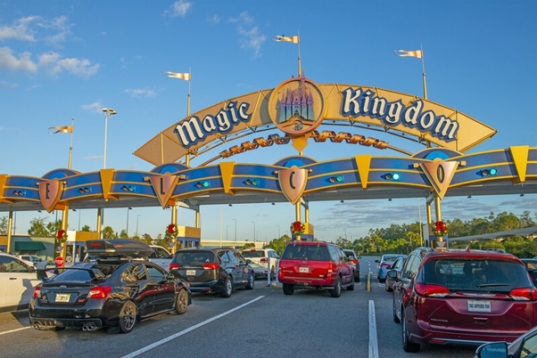 A car is parked in front of the magic kingdom entrance.